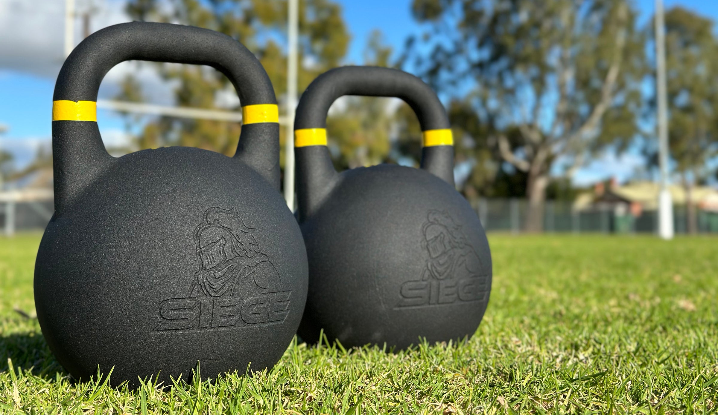 SIEGE matte black powder coat cast iron competition kettlebell 16kg pair on green grass